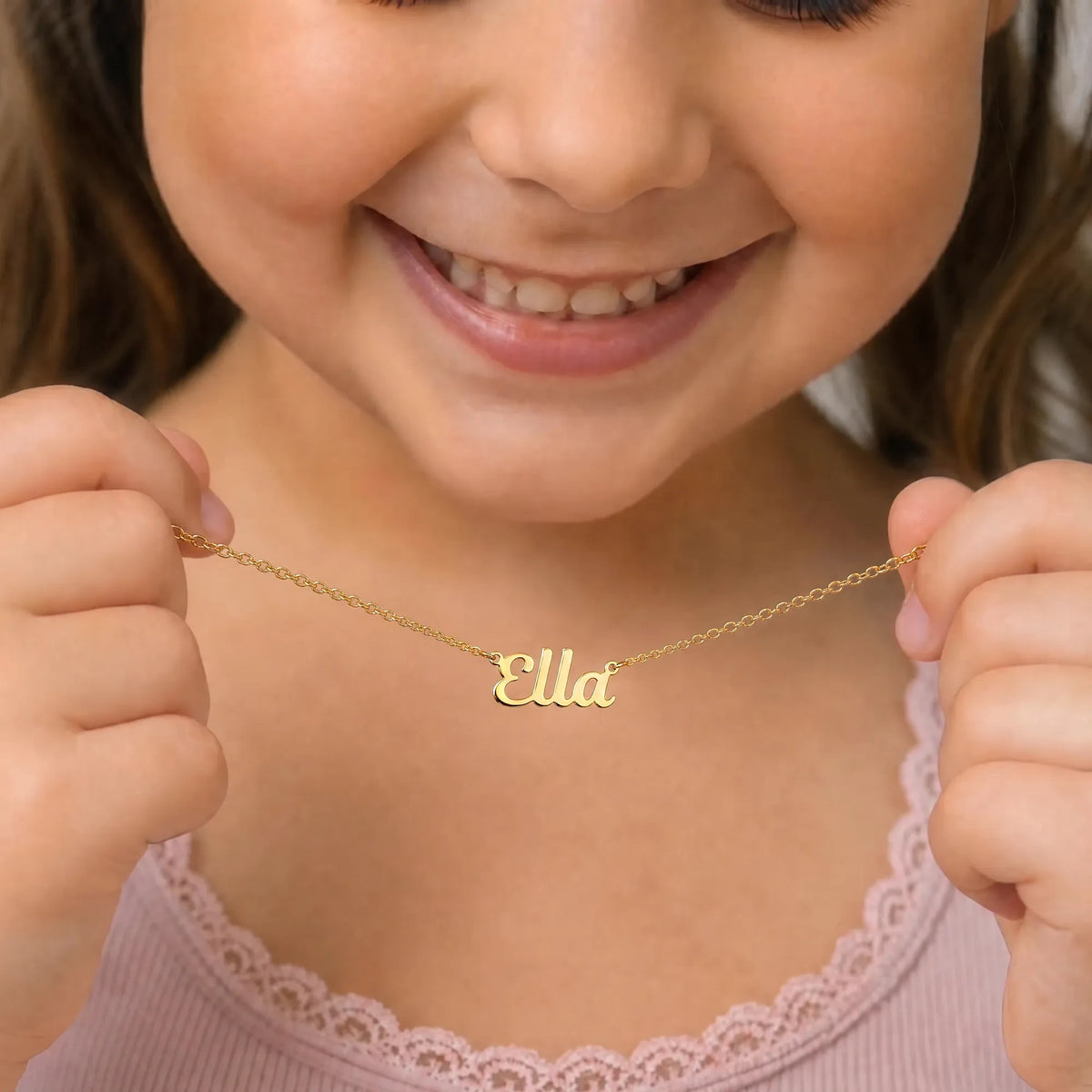 Child holding gold Ella name necklace - Bella font
