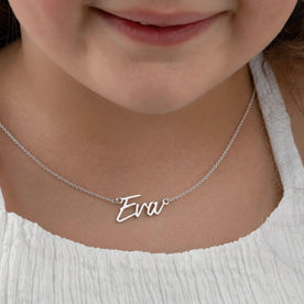 Child with white top wearing a silver 'Eva' personalised name necklace