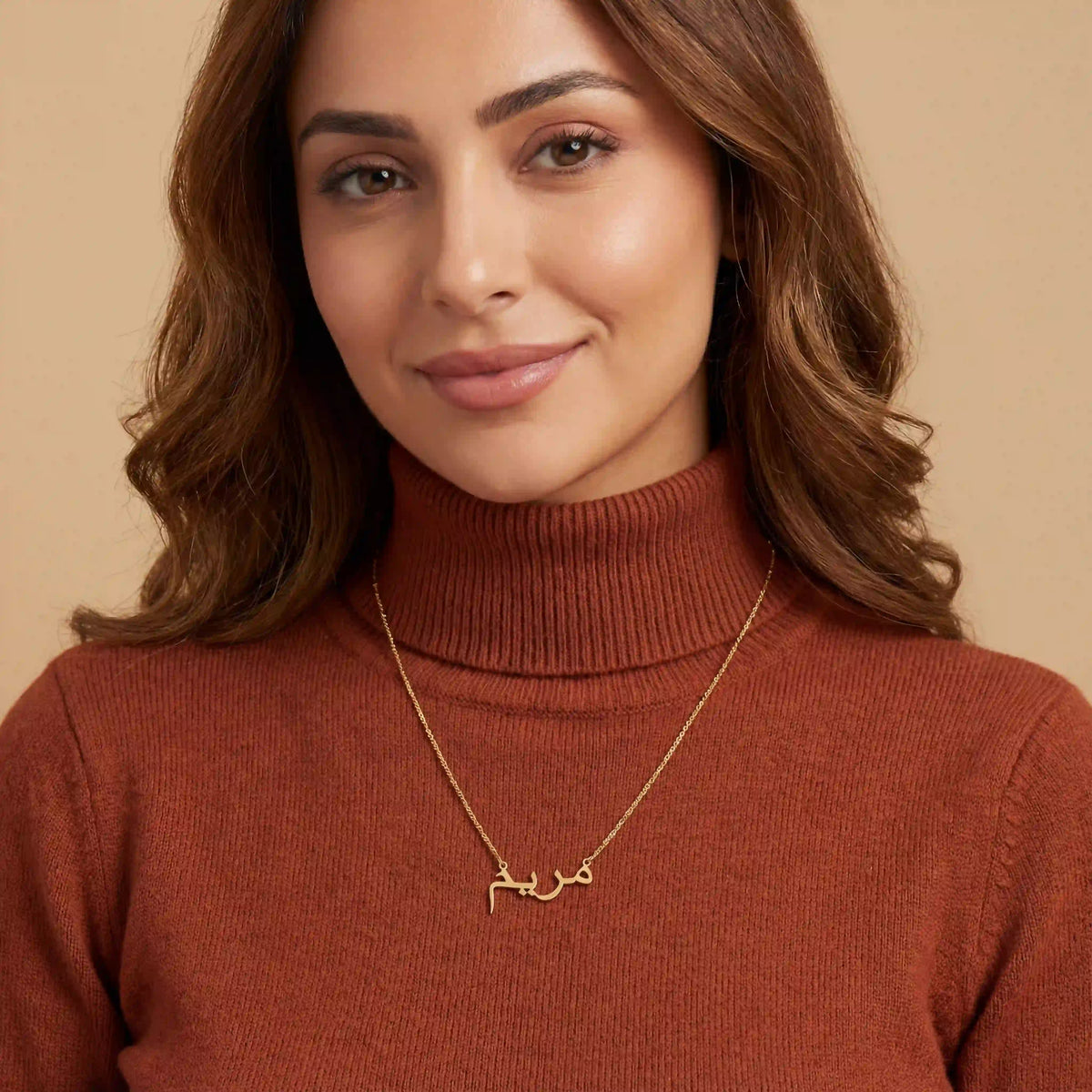 Woman in a rust turtleneck wearing a gold personalised Arabic name necklace
